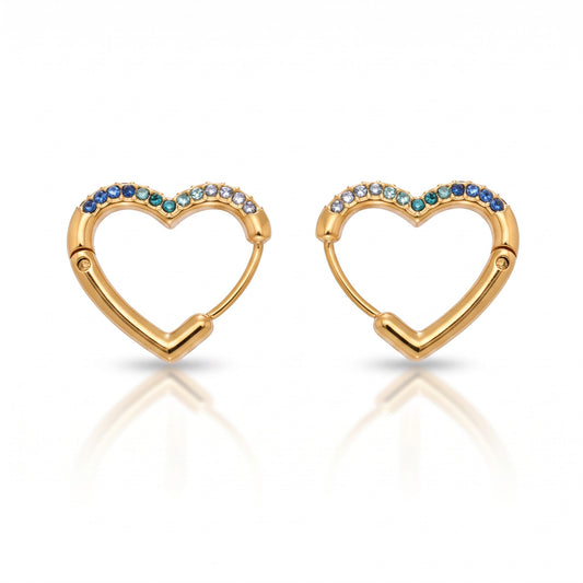 Meinara Lina heart-shaped gold hoop earrings featuring a gradient of blue and white crystals on a white background