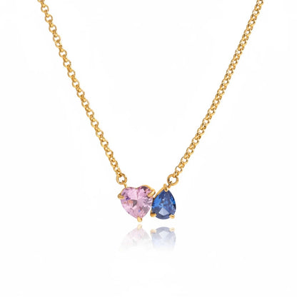 Meinara Maya necklace featuring a blush-pink heart-cut crystal and a deep-blue pear-cut crystal on a gold chain.