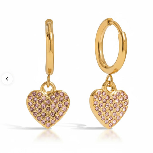 Meinara Nova hoop earrings in gold featuring dangling heart-shaped charms encrusted with small pink crystals